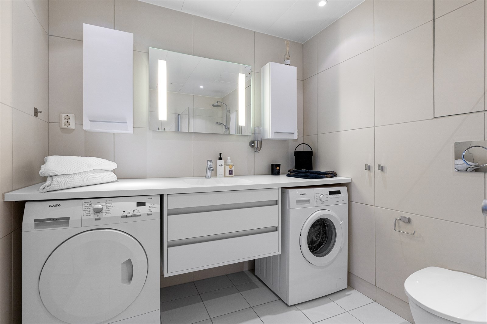 Opplegg for både vaskemaskin og tørketrommel, samt godt med lagringsplass i skuffer og skap Galleribilde