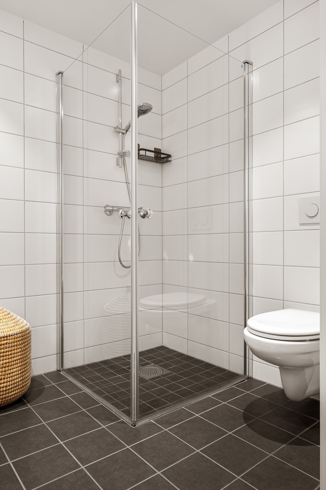 - Badet inneholder vegghengt toalett, benkeskap med servant og dusjdører i glass - Galleribilde