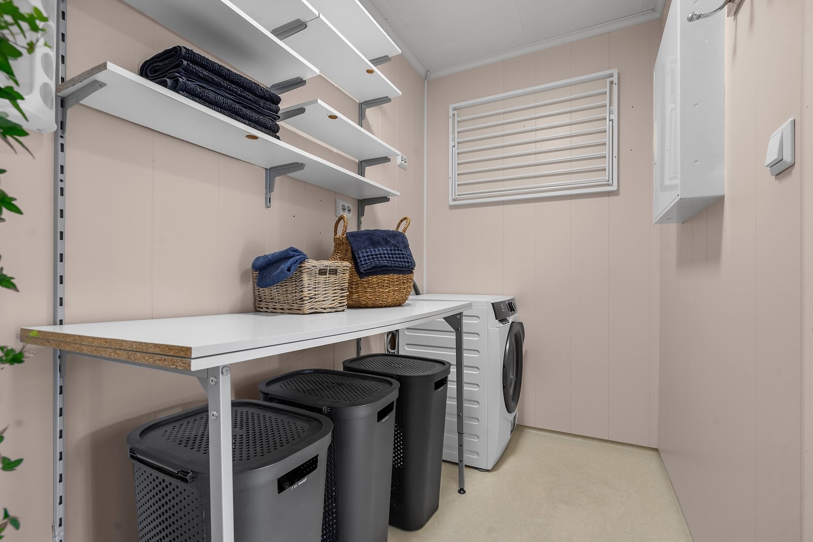 Boligen inkluderer et praktisk separat vaskerom, perfekt for effektiv og organisert klesvask. Rommet er utstyrt med en arbeidsbenk, hyller for oppbevaring, samt opplegg for både vaskemaskin og tørketrommel. Galleribilde