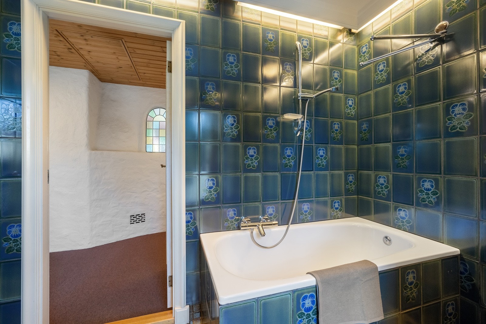 Badet er flislagt og fra byggeår, innredet med innmurt badekar og dusj. Galleribilde