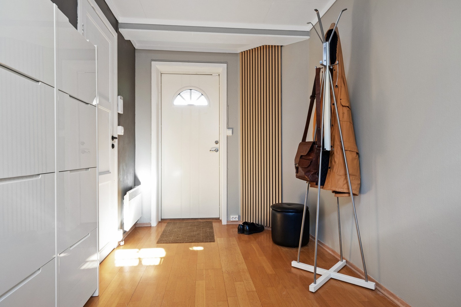 I underetasjen er det en pen, godkjent utleiedel med egen inngang. Innenfor en hvit ytterdør fra 2019 er det en fin entré med gråmalte vegger, en spilekledd kontrastvegg og parkett på gulvet. Galleribilde