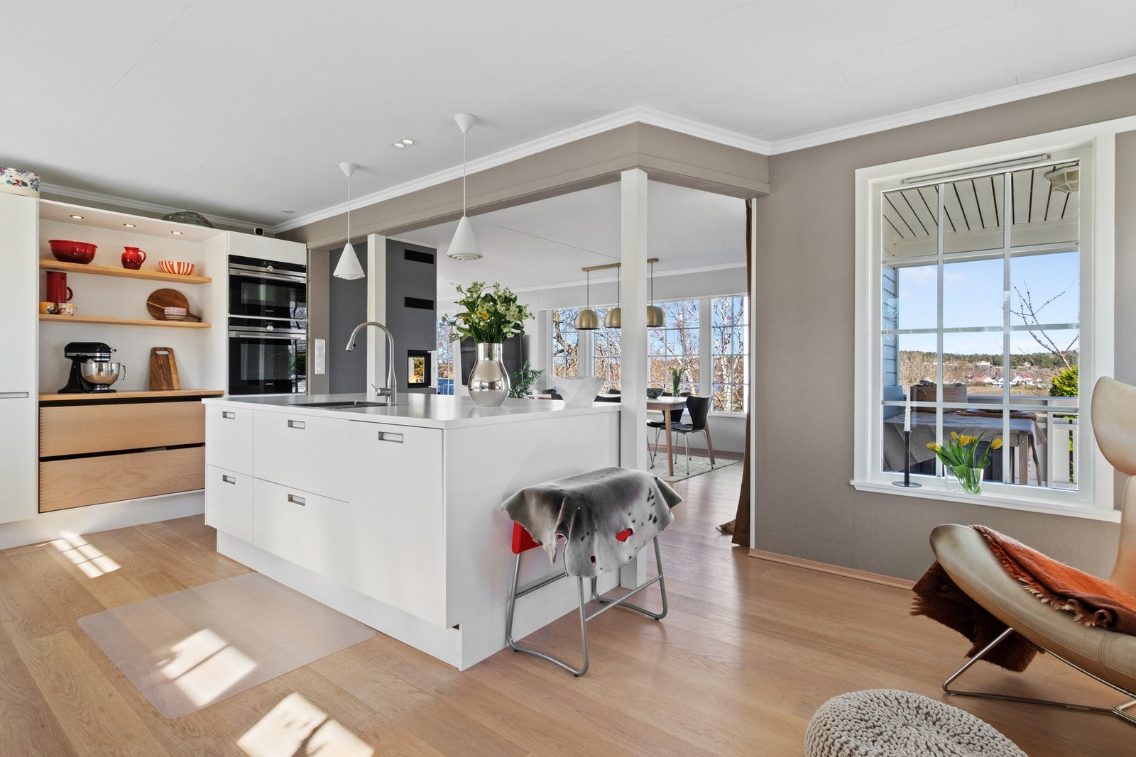 Innredningen fra Svane Kjøkken har hvite, glatte fronter, bøkeskuffer og hvit benkeplate med planlimt kum i stål. Galleribilde