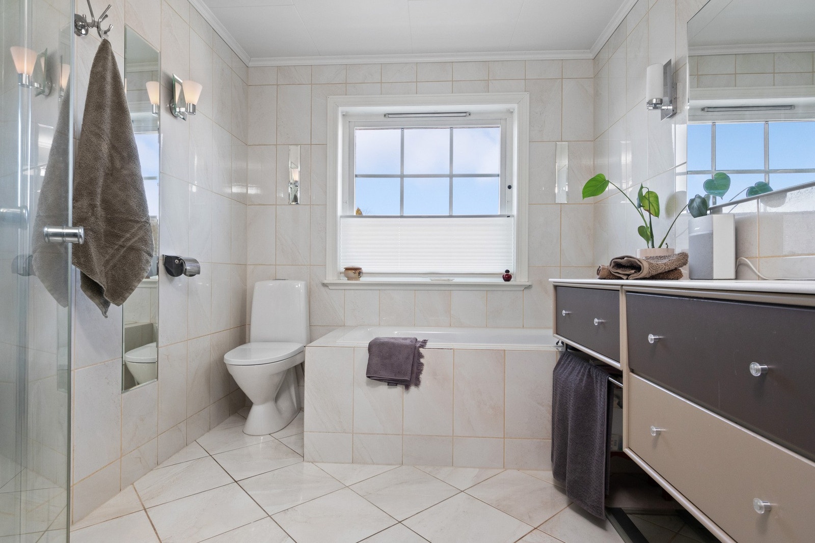 Badet i første etasje fremstår som velholdt og pent, med lyse fliser på veggene og matchende fliser på gulv med gulvvarme. Galleribilde