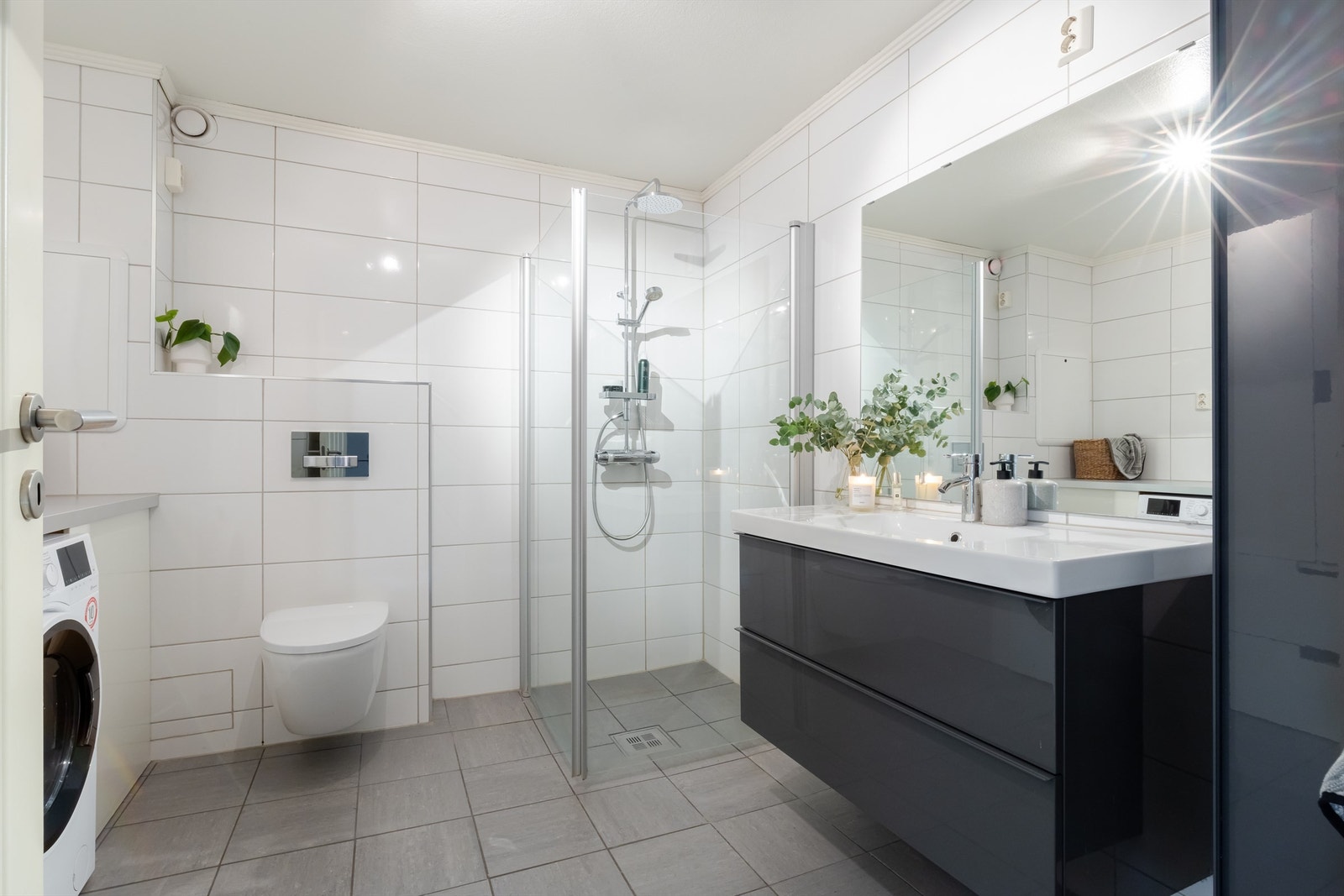 Romslig og tidløst bad med varmekabler i gulv og opplegg til vaskemaskin. Galleribilde