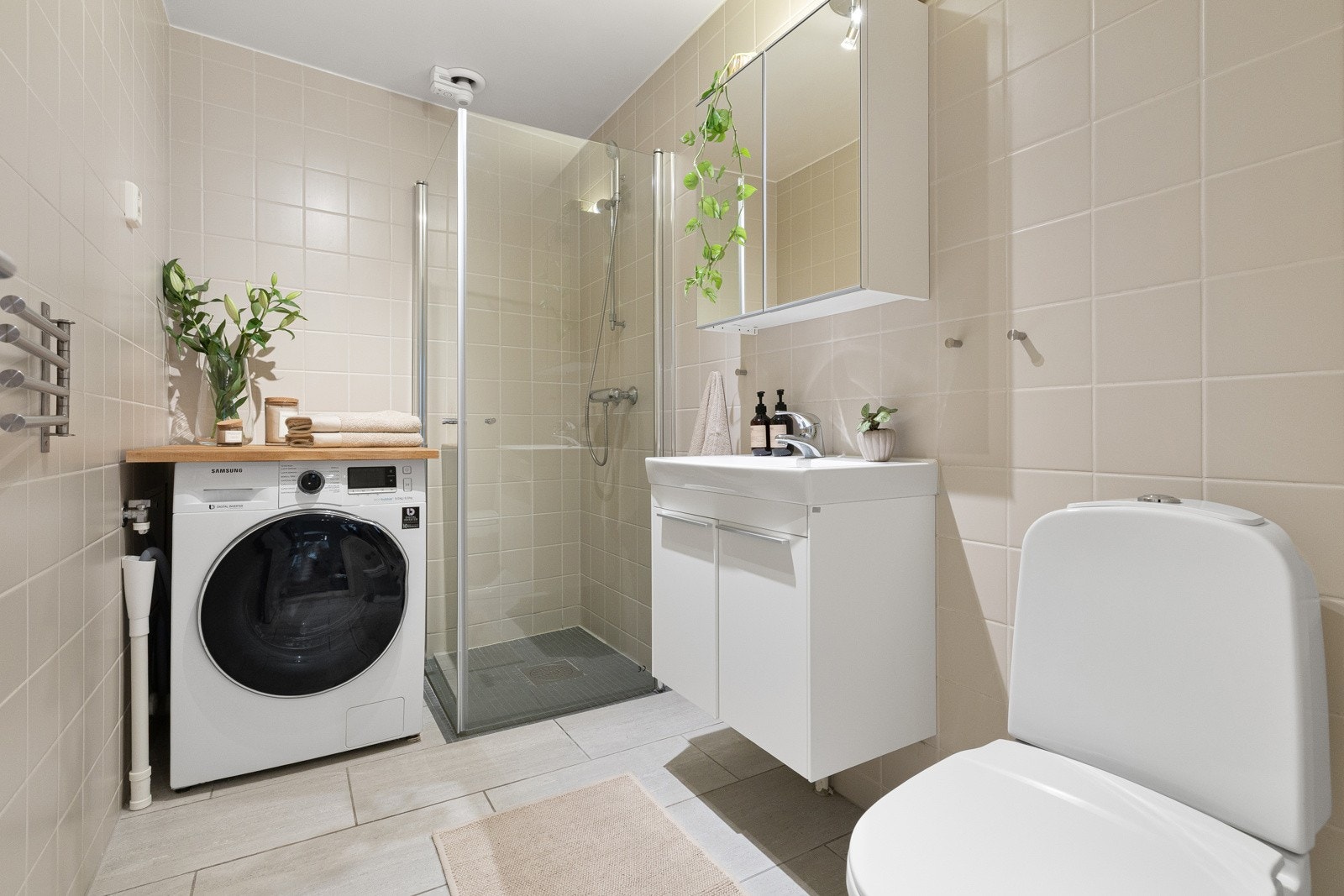 Pent flislagt baderom med behagelige varmekabler i gulv og opplegg for vaskemaskin. Galleribilde