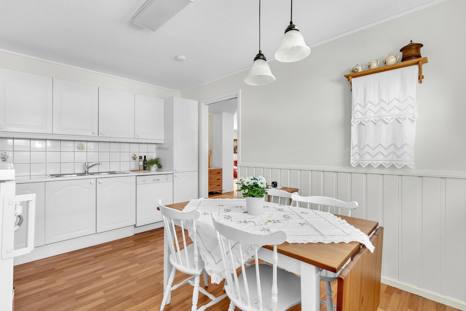 Her får du et kjøkken fra byggeåret 1995 bestående av kjøkkeninnredning med hvite profilerte fronter og benkeplate av slitesterk laminat, samt fliser på vegg mellom kjøkkenbenk og overskap. Galleribilde