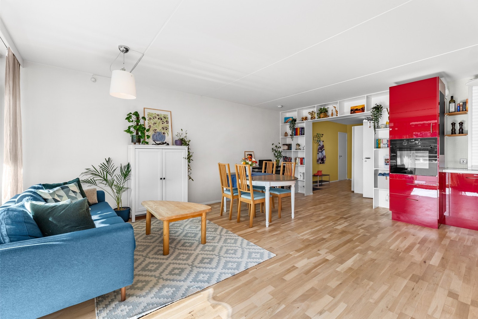 Stue og kjøkken er i åpen løsning med en bred åpning fra gangen, som skaper en romslig og sosial sone. Hyllene som strekker seg over åpningen brukes i dag til bøker og dekor. Galleribilde
