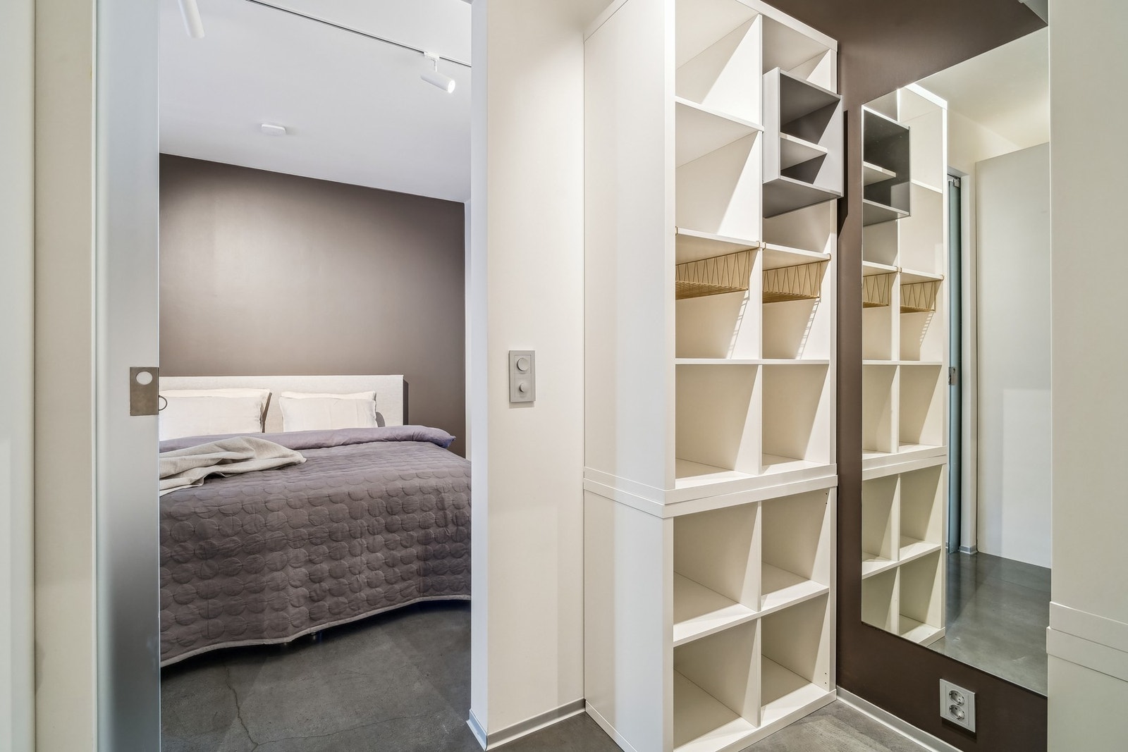 Garderoben er plassert mellom badet og soverommet, innredet med hyller og stenger for oppheng. Galleribilde