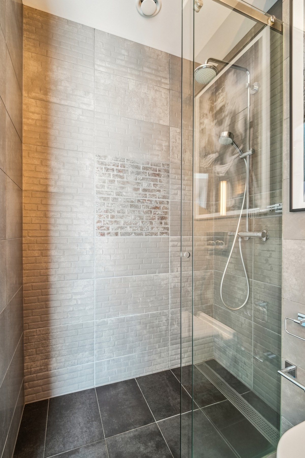 Badet har et dusjhjørne med regnfallsdusj og skyvedør av glass. Galleribilde