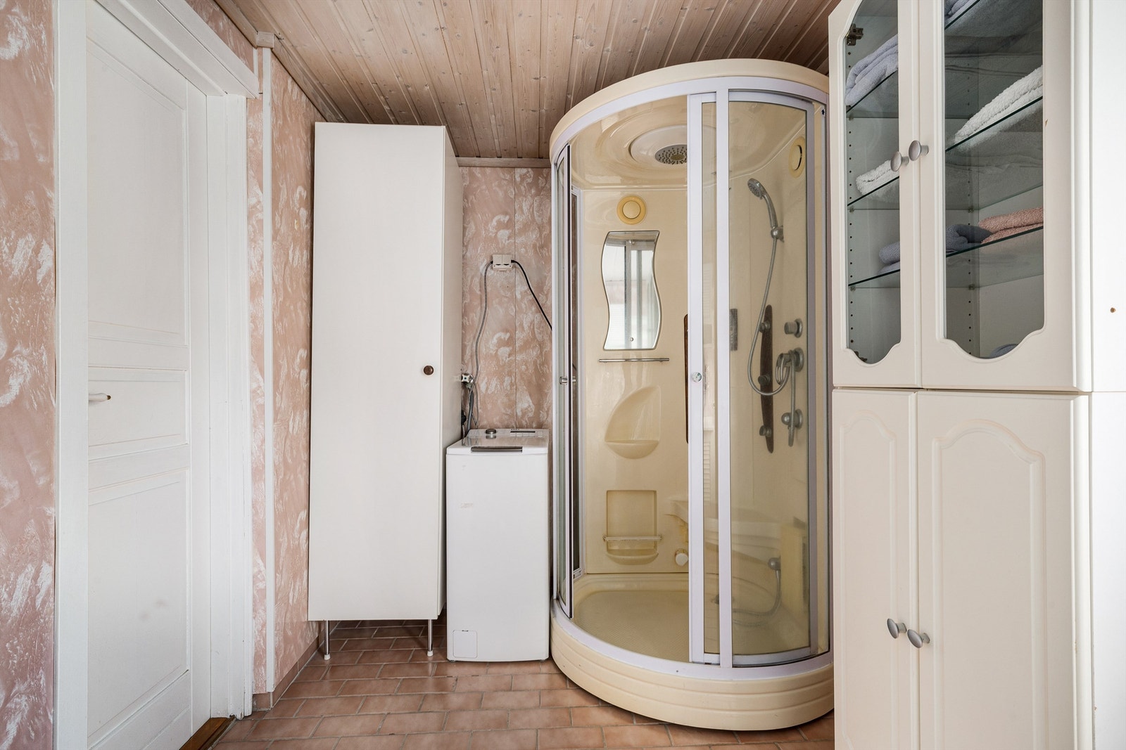 Badet med flislagt gulv og retro respatexplater på veggene er utstyrt med opplegg til vaskemaskin, dusjkabinett og servant i seksjon også den med retropreg. Galleribilde