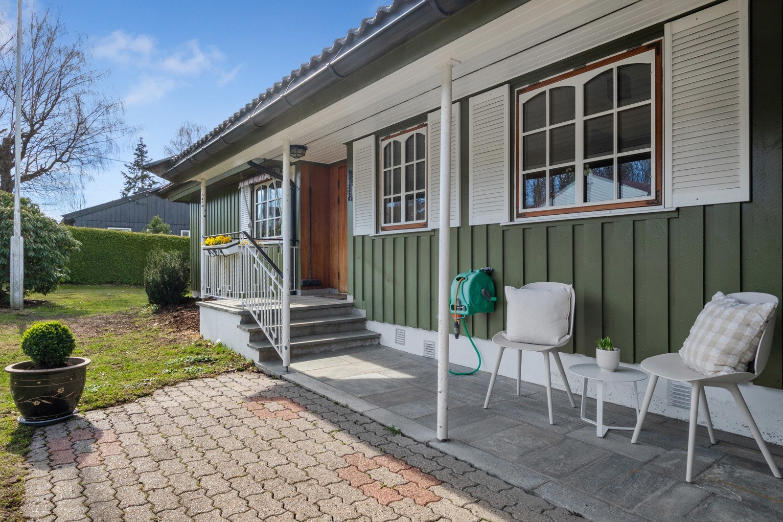 Ytterdøren er overbygd og utstyrt med belysning, og ved inngangen har boligen utekran og plass til benker eller kafésett. Galleribilde