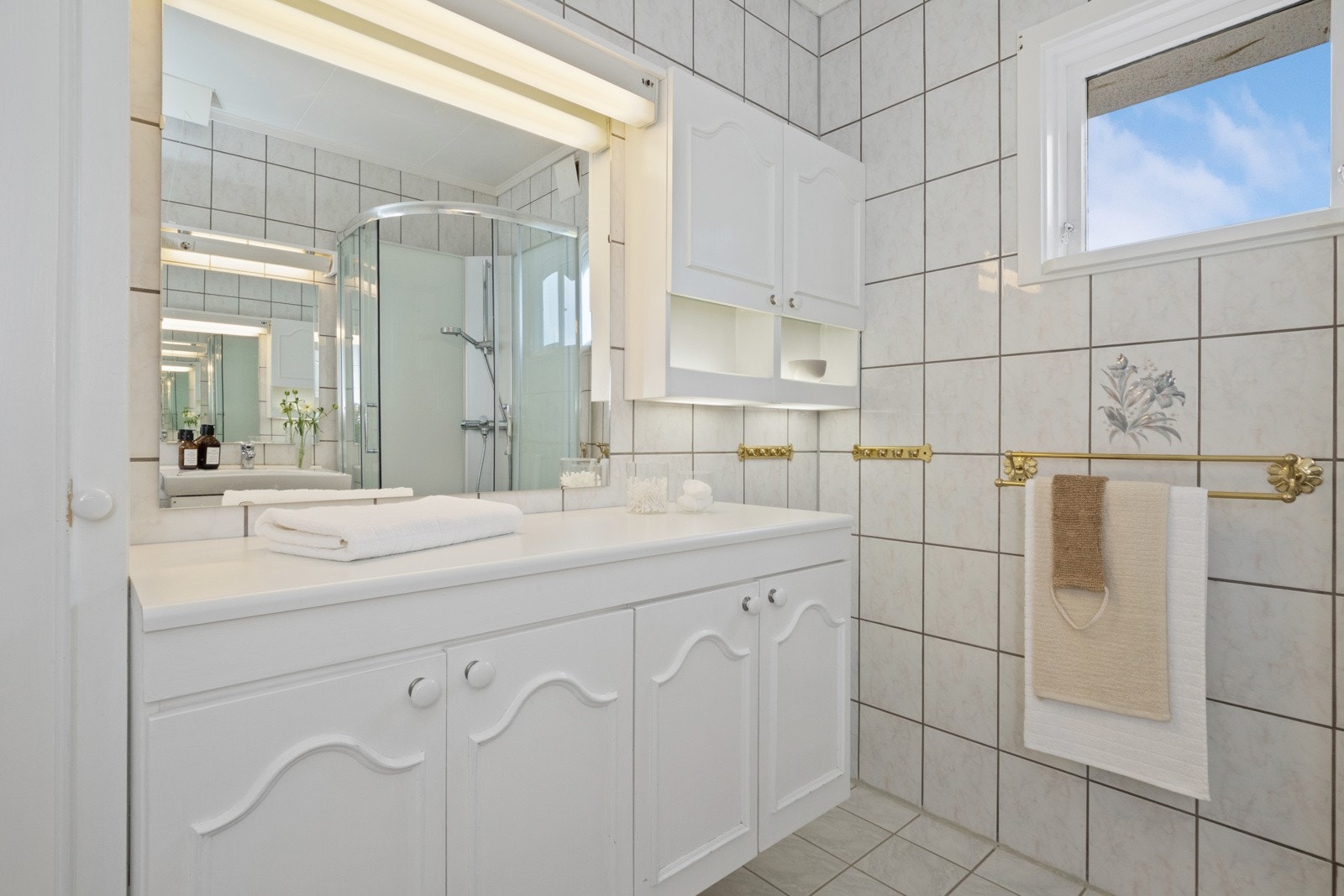 To hvite skapinnredninger er plassert under hvert sitt speil med belysning, ett med servant og ett med tilhørende høy- og veggskap. Galleribilde