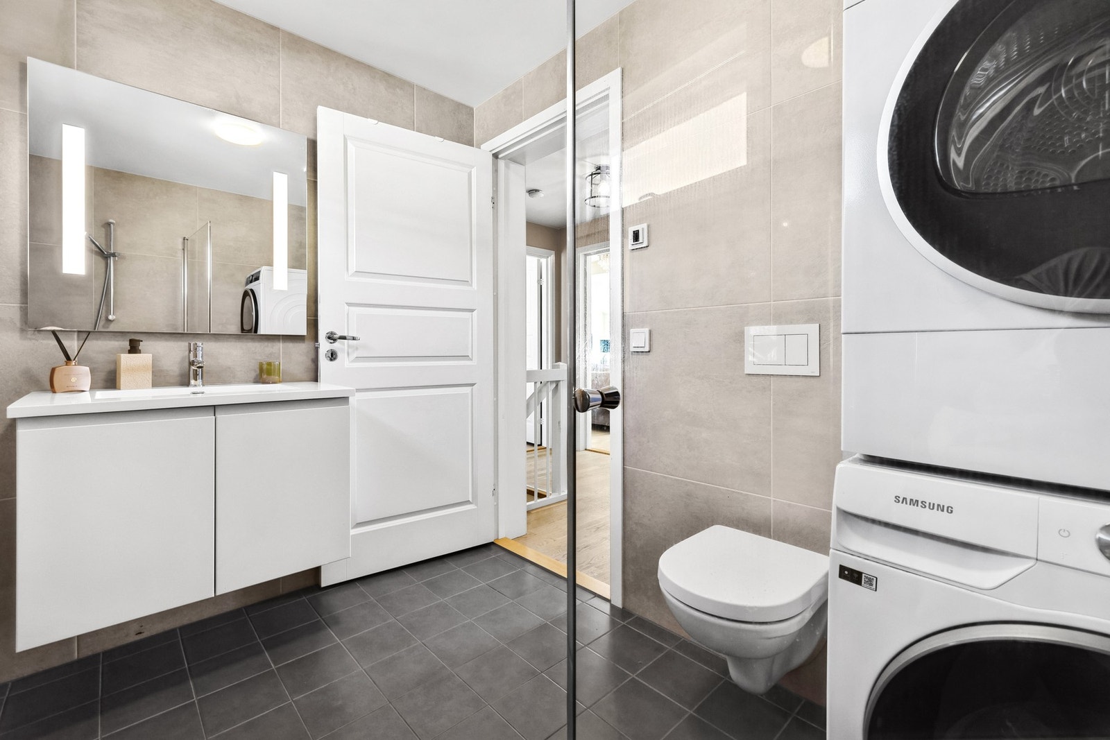 Badet har fliser på gulv og vegger, servant med underskap for ekstra oppbevaring, opplegg for vaskemaskin, vegghengt toalett osv. Galleribilde