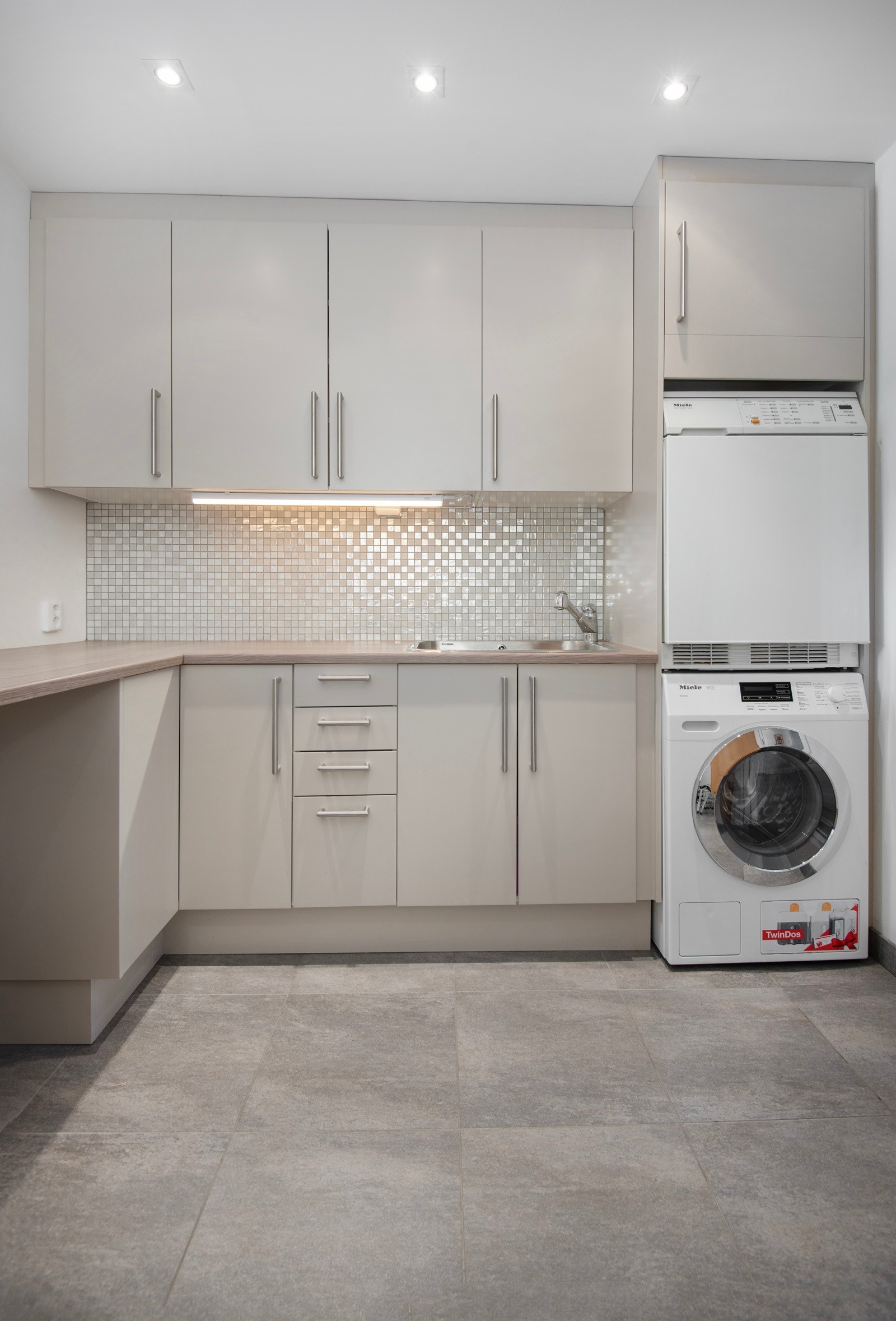 Et pent vaskerom med praktisk innredning og opplegg for vaskemaskin. Galleribilde