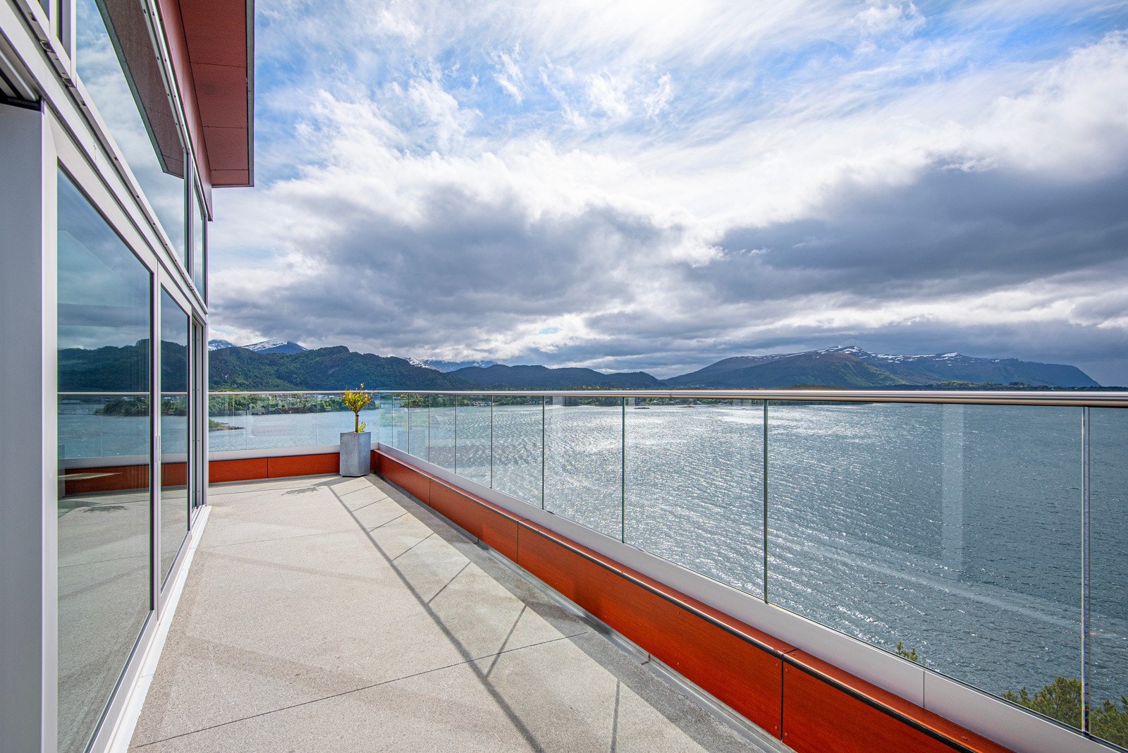 Stor solterrasse med støpt dekke, glassrekkverk og panoramautsikt. Galleribilde