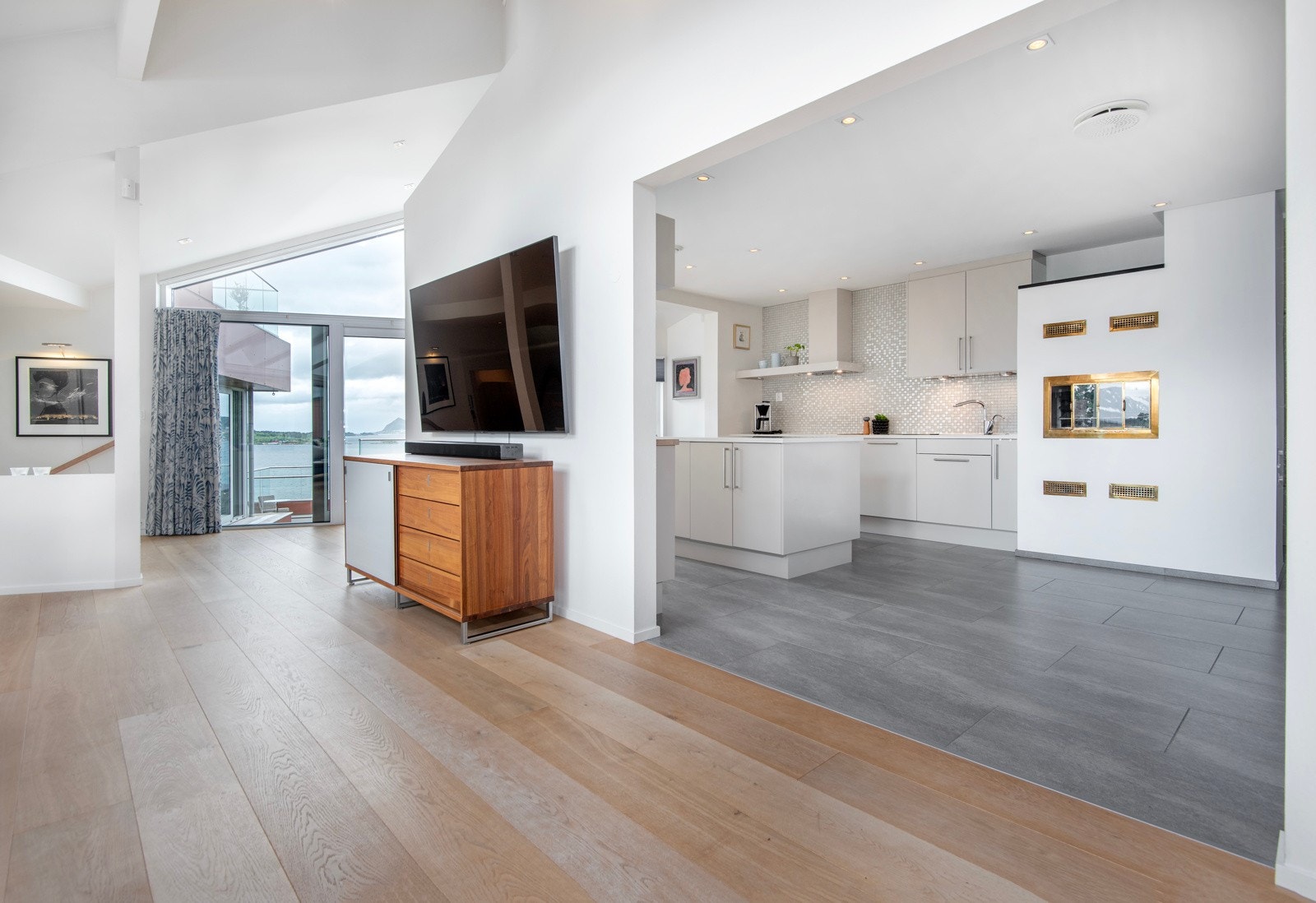 Det er delvis åpen løsning mellom stue og kjøkken. Legg merke til peisen på kjøkkenet. Galleribilde