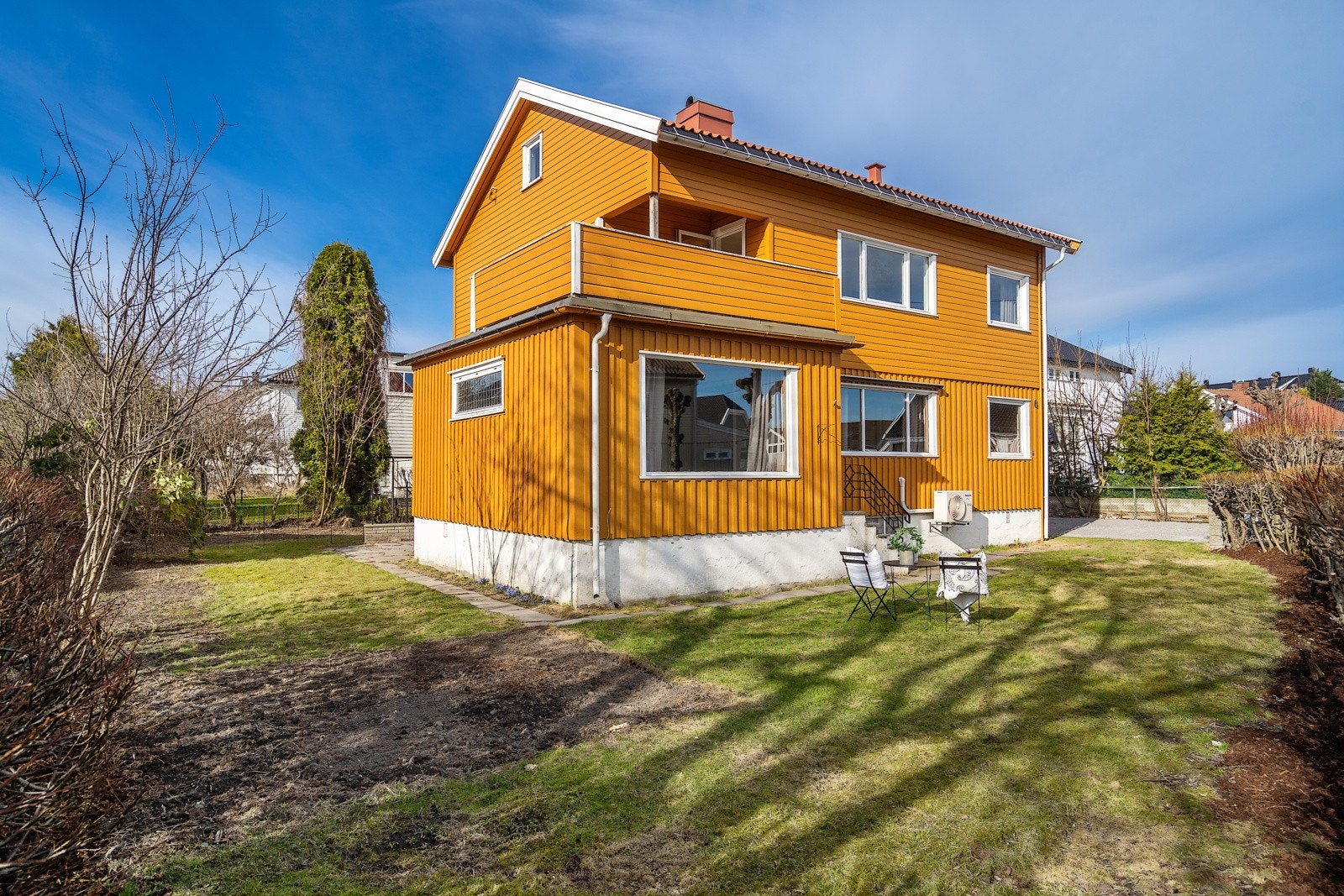 tomannsboligen er tomten opparbeidet med stor gressplen, steinlagte gangstier og en port ut til veien. Hagen blir fint rammet inn av hekker. Galleribilde