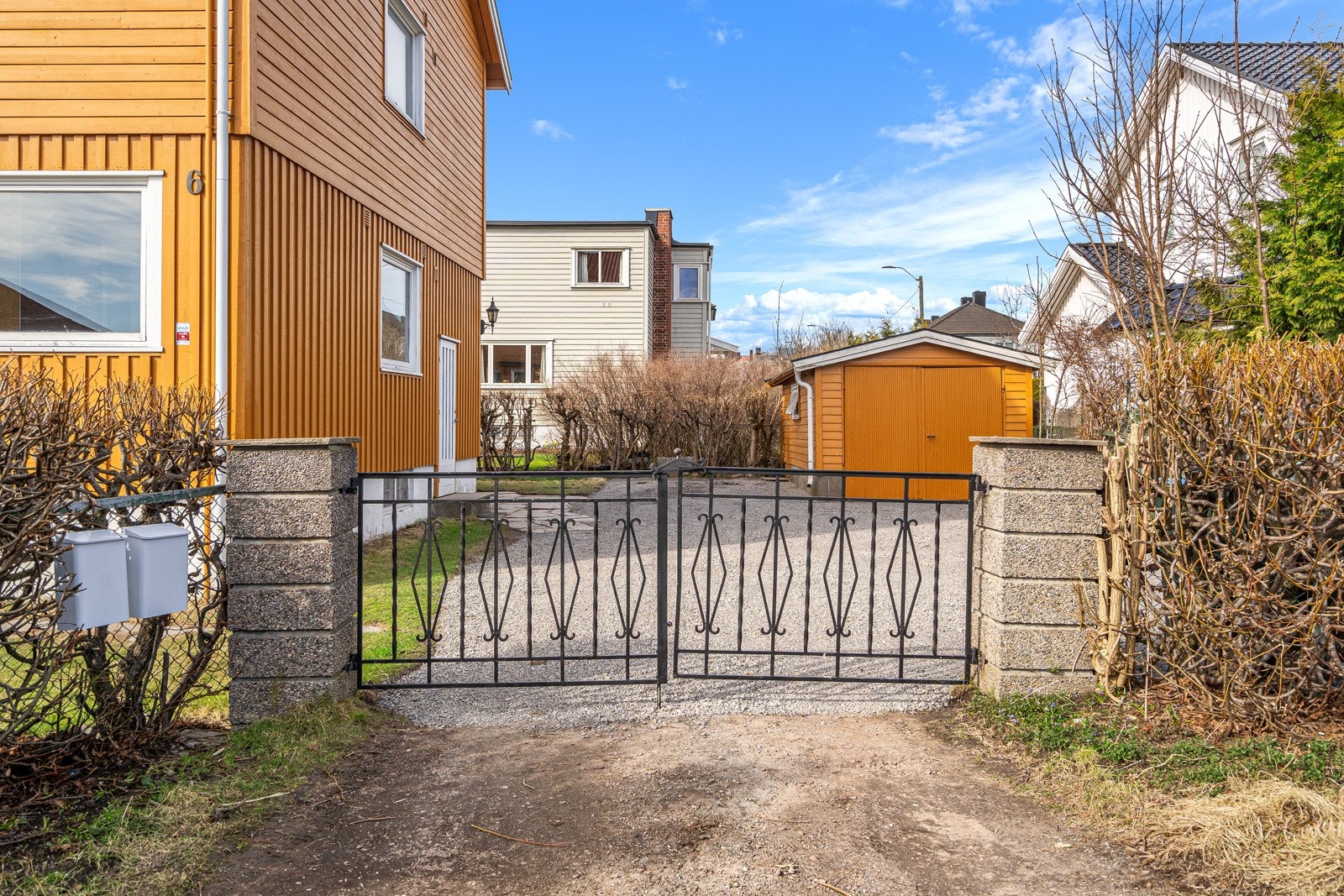Porten fører inn til en gruslagt gårdsplass, der boligen disponerer en garasje på ca. 19 kvm. Galleribilde