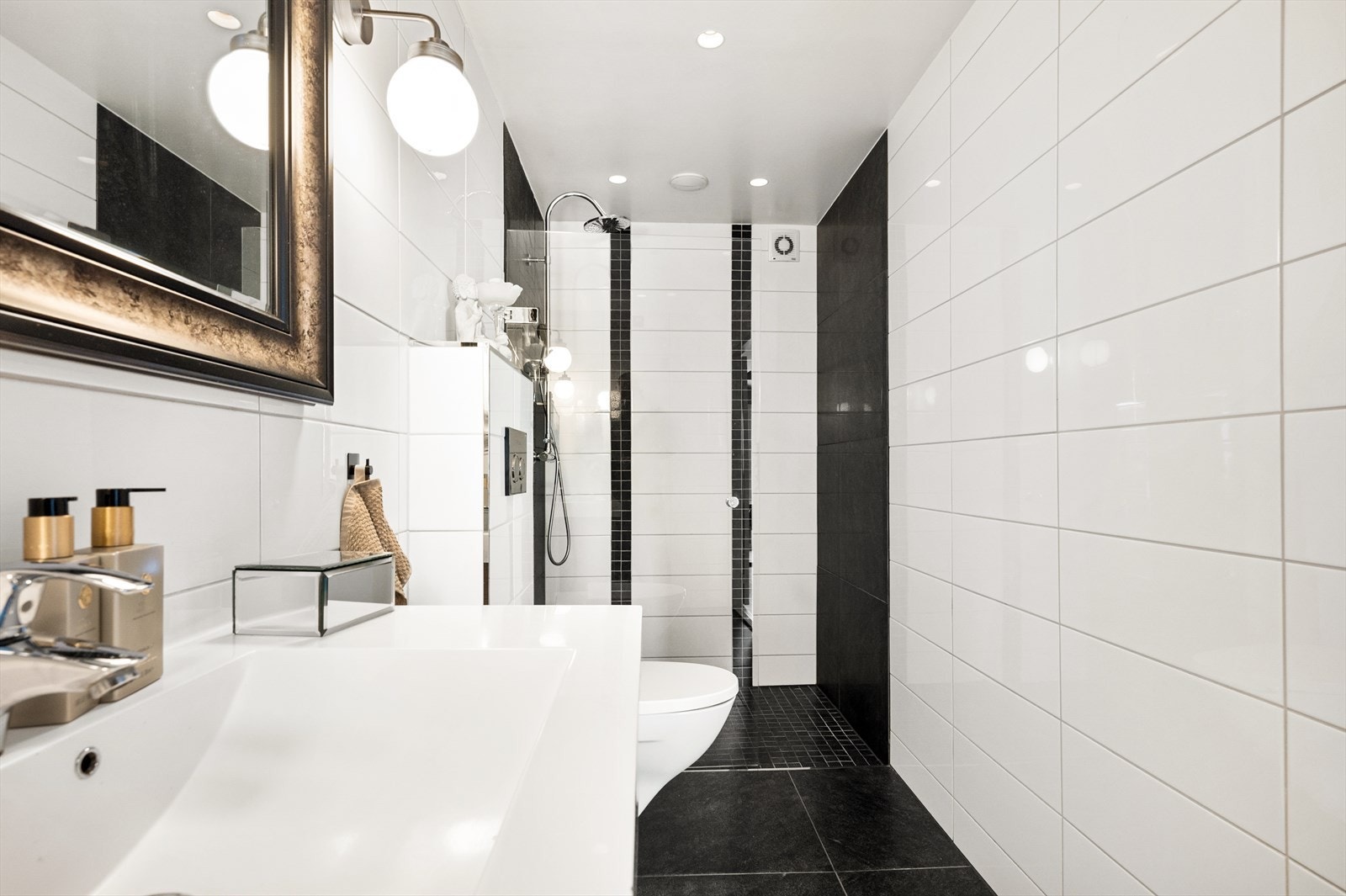 Badet er innredet med benkeskap med servant, dusjdør og vegghengt toalett Galleribilde