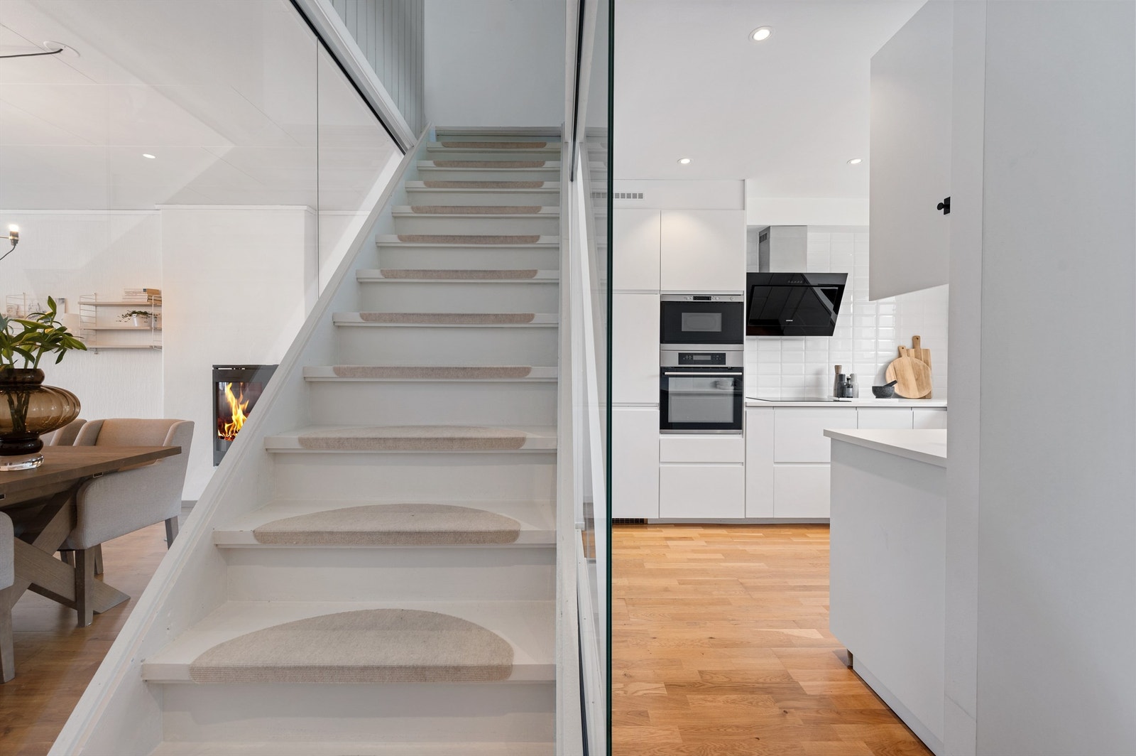 Boligen har blitt pusset opp og de stilige glassveggene rundt trappen gir lys gjennom boligen samtidig som den deler stue og kjøkken i ulike soner. Galleribilde
