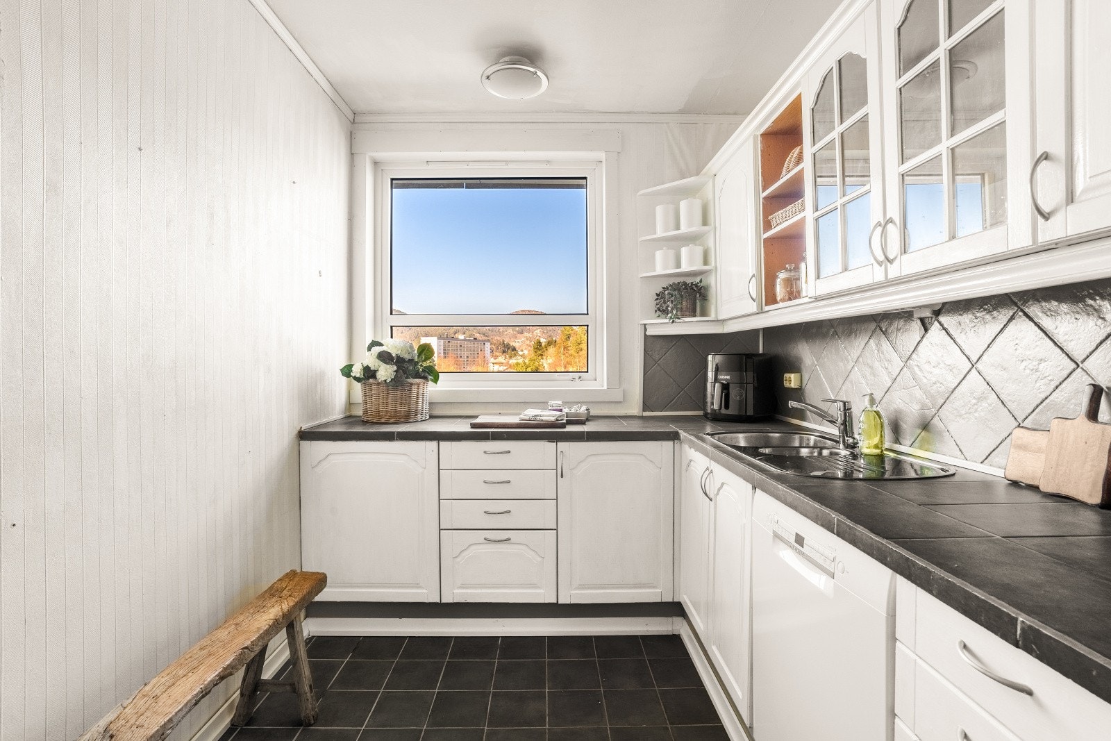 Du finner profilerte fronter på kjøkkeninnredningen, og ett av overskapene har glassfront for lett oversikt. Galleribilde