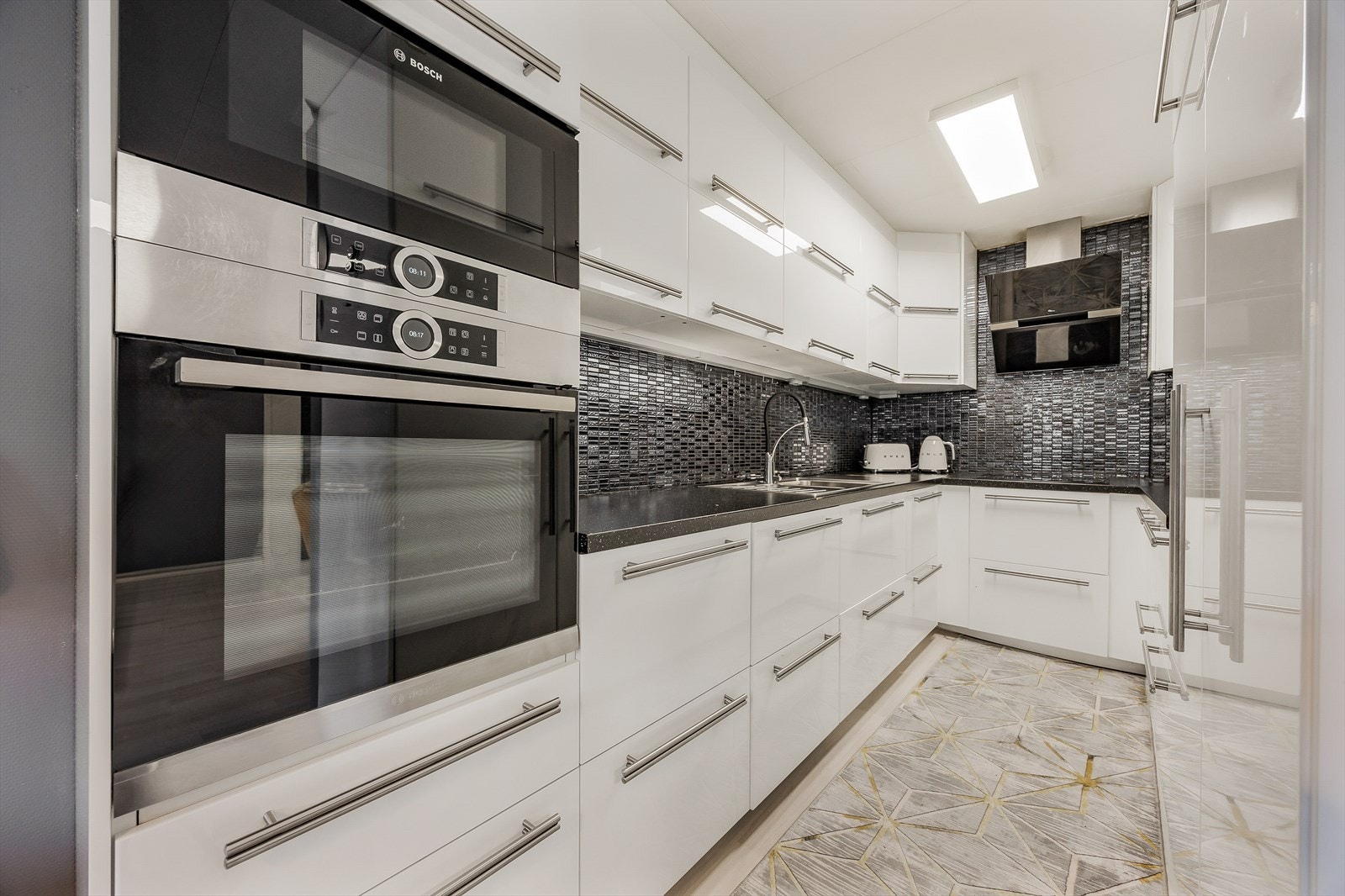 Velutstyrt og moderne U-kjøkken med takhøye skap og massevis av arbeidsplass. Galleribilde