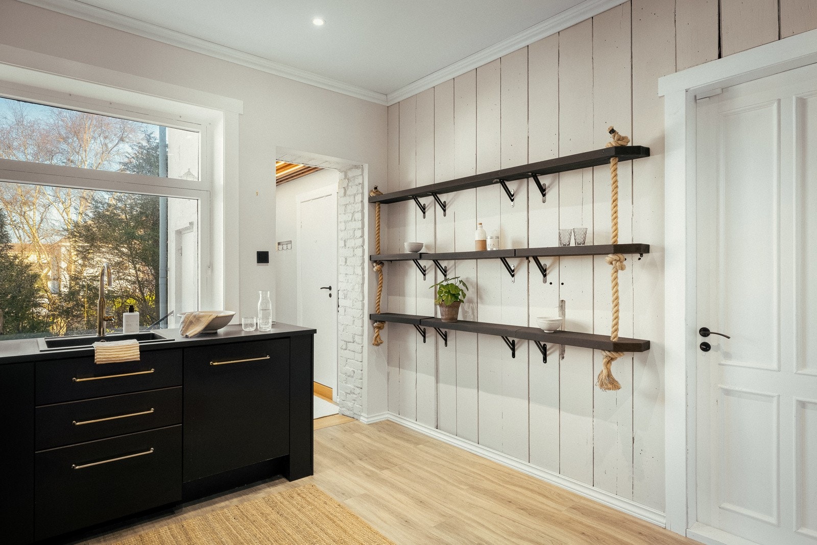 Ikea-innredningen har sorte, glatte fronter, gulldetaljer og benkeplate av laminat med nedfelt oppvaskkum. Galleribilde