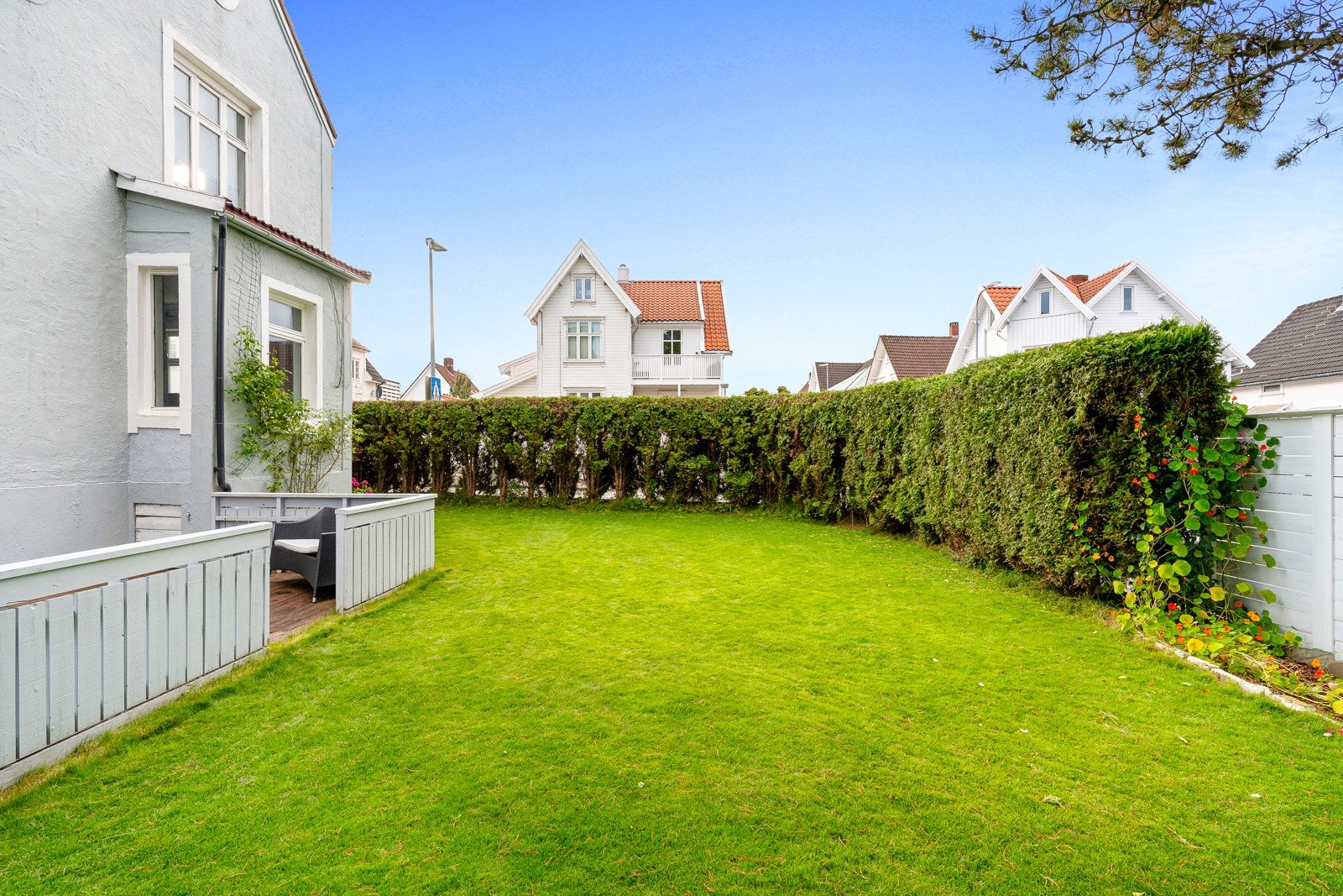 Den rammes fint inn av et høyt gjerde og en velstelt tujahekk, og hagen er et stort pluss for hele familien, med mye plass til lek og moro hele året. Galleribilde