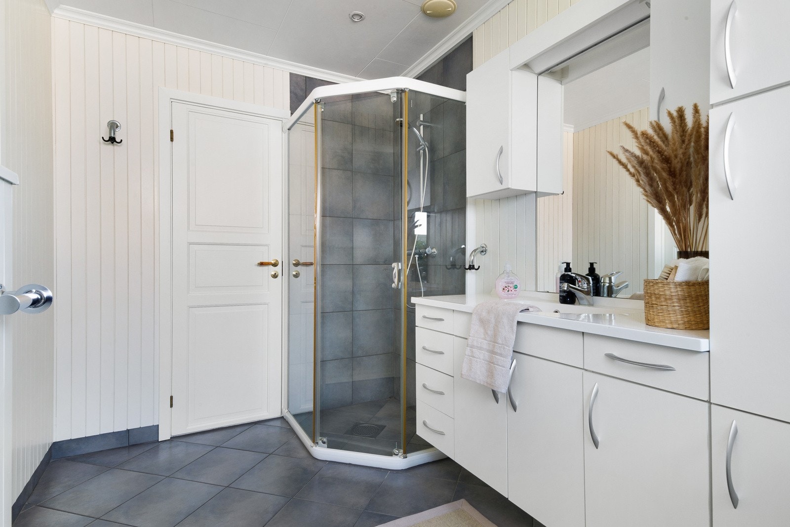 Badet er praktisk innredet med dusjhjørne, vegghengt WC og vask i seksjon. Galleribilde