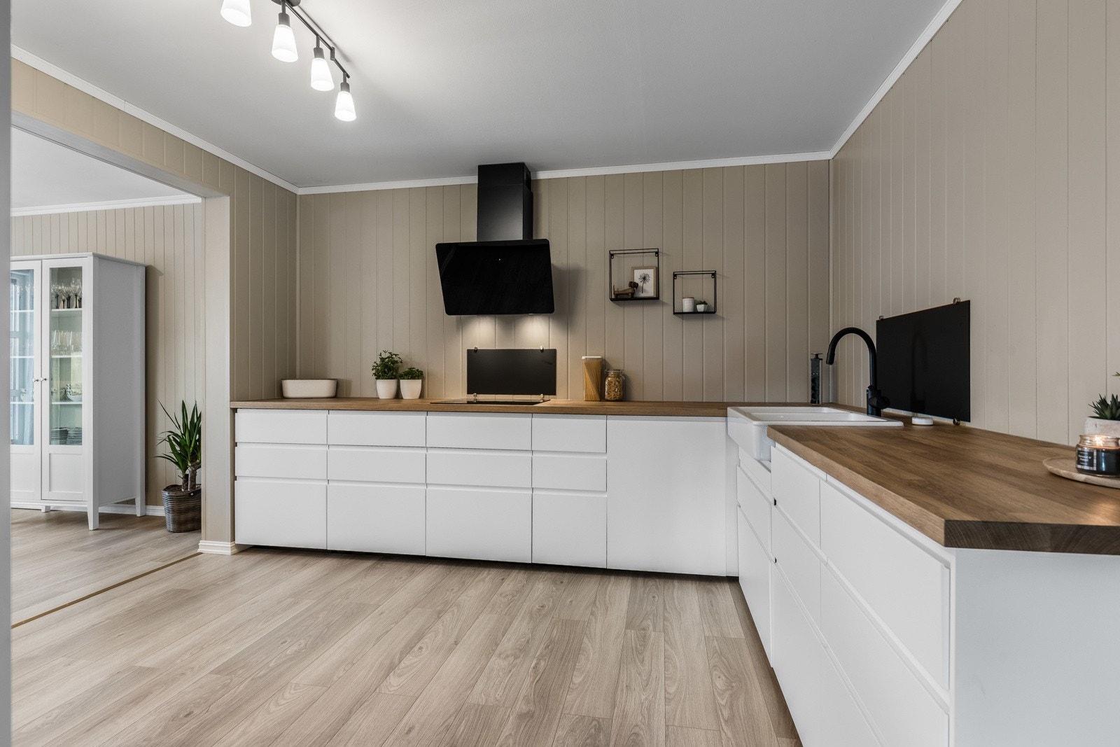 Ikea-innredningen fra 2024 er stilren og moderne, med hvite, glatte fronter, store høyskap og dobbel oppvaskkum nedfelt i en heltre benkeplate. Galleribilde