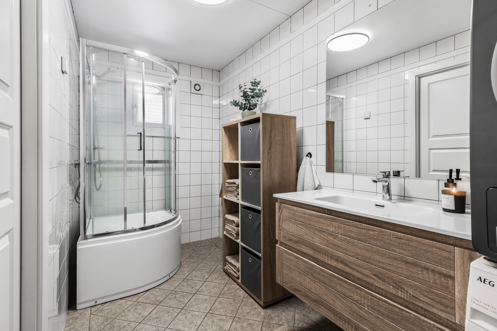 Planløsningen er praktisk med et bad i hver etasje. Badet nede har hvite veggfliser i kombinasjon med lysegrå fliser på gulvet. Galleribilde