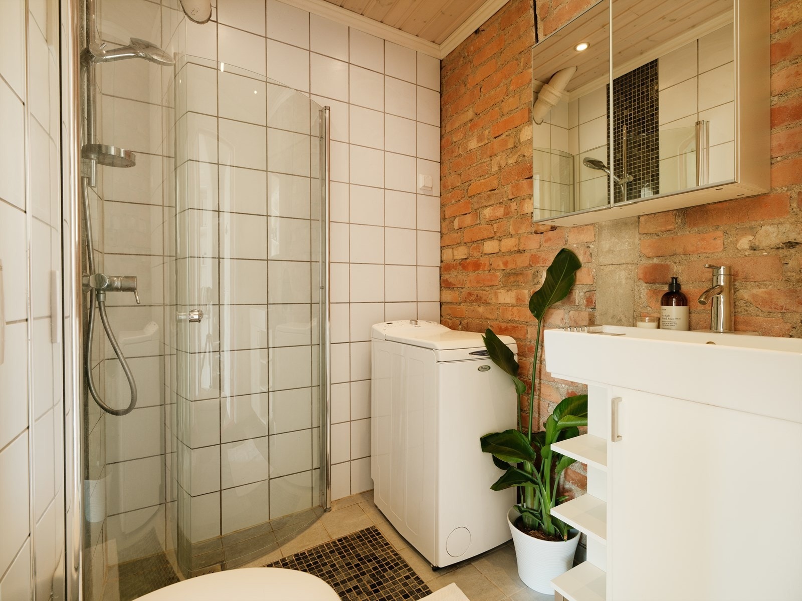 Romslig bad med dusj, opplegg til vaskemaskin, servant og toalett. Galleribilde