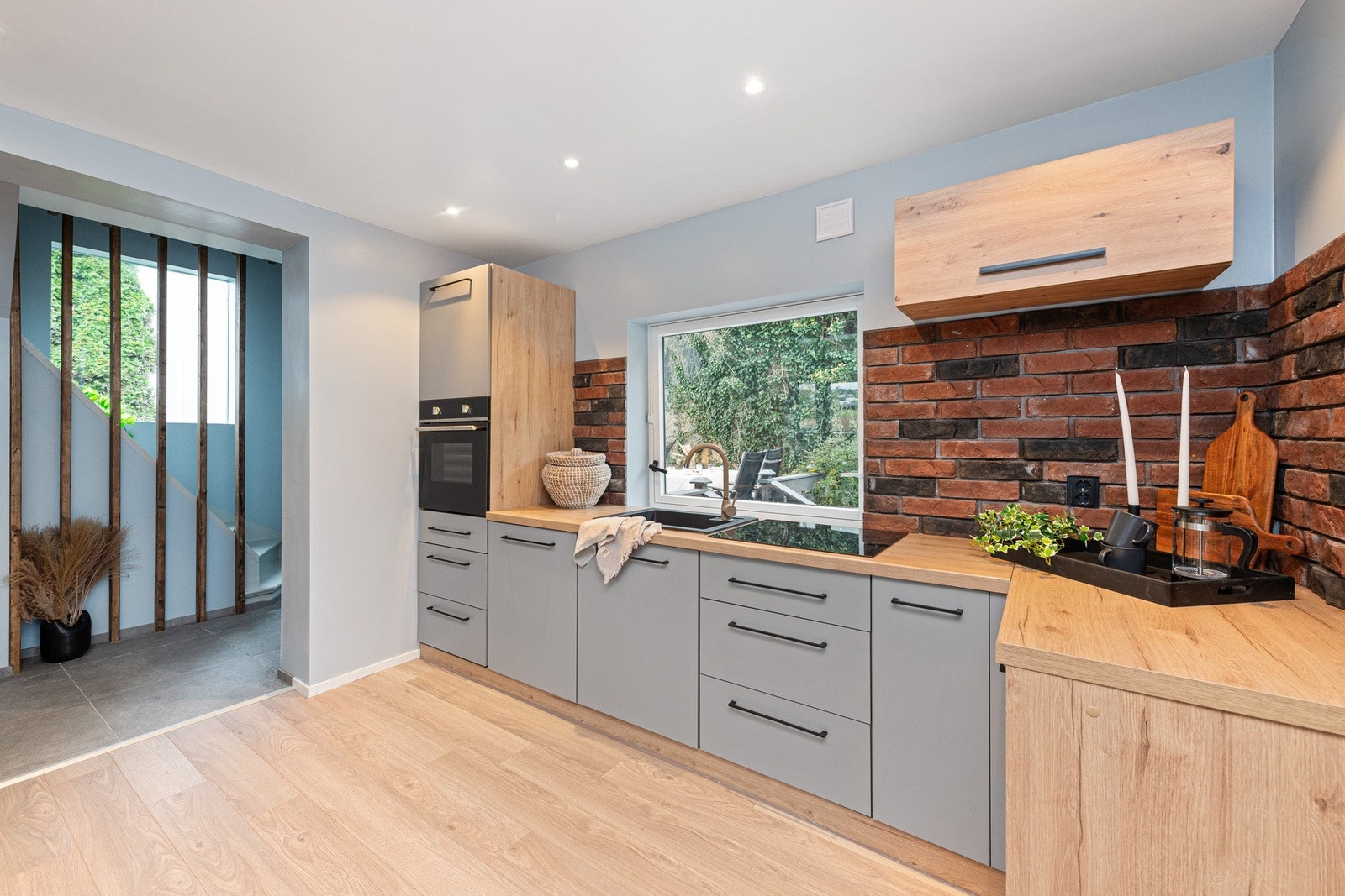 Nedfelt oppvaskkum i komposittmateriale med ett-greps armatur. Dekorstein mellom benkeplate og overskap med stikkontakter. Integrert platetopp, stekeovn og oppvaskmaskin. Galleribilde