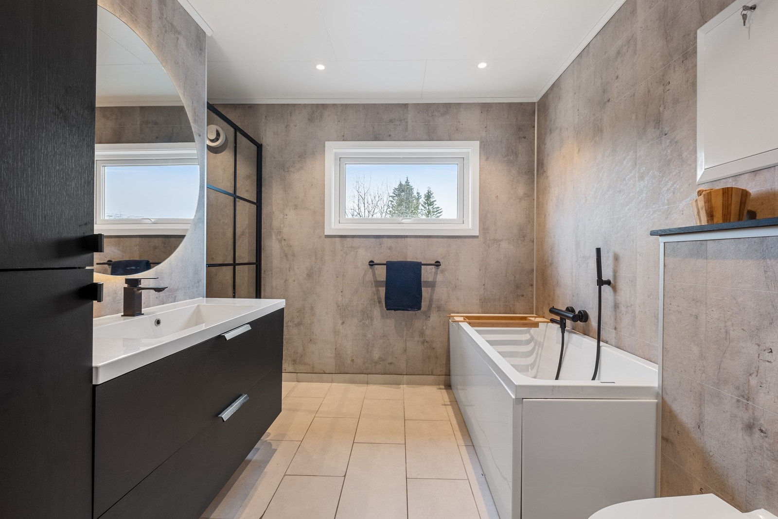 Badet i 1. etasje har et flislagt gulv og baderomsplater på vegg. Moderne utstråling med spotter i taket, badekar og egen dusjsone. Galleribilde