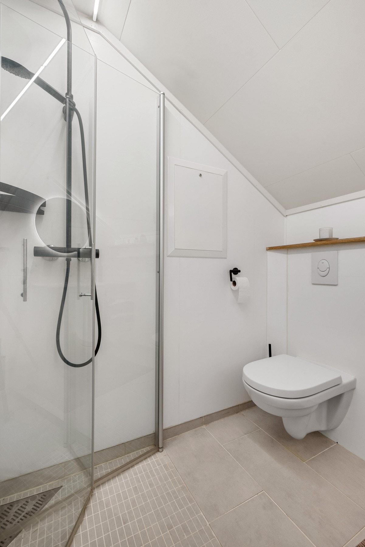 Stilrent og tidløst bad utstyrt med vegghengt toalett, servant og dusjnisje. Galleribilde