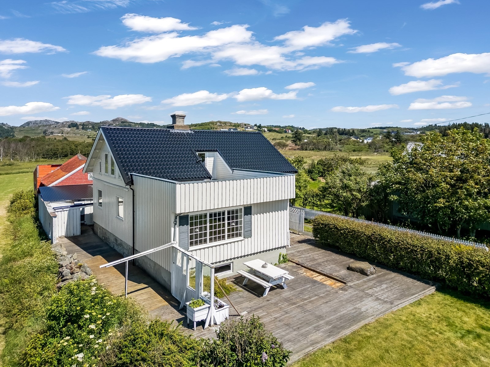 Fasade av huset og terrasse med overgang til plenområde. Galleribilde
