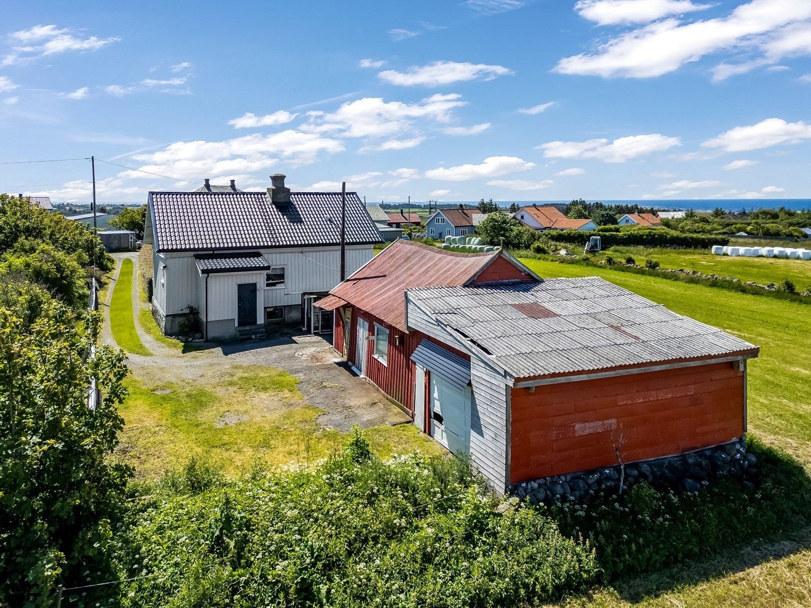 Fasade bak huset med eldre driftsbygning og garasje. Galleribilde