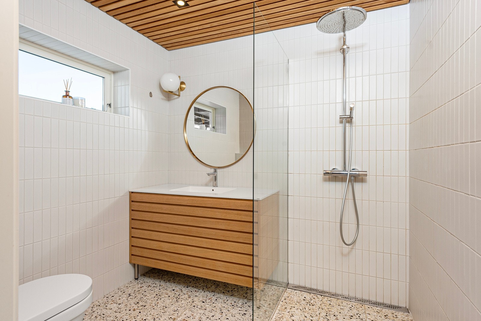 Delikat baderom fra 2020 med flislagt gulv med varmekabler og himling med eikespiller. Galleribilde