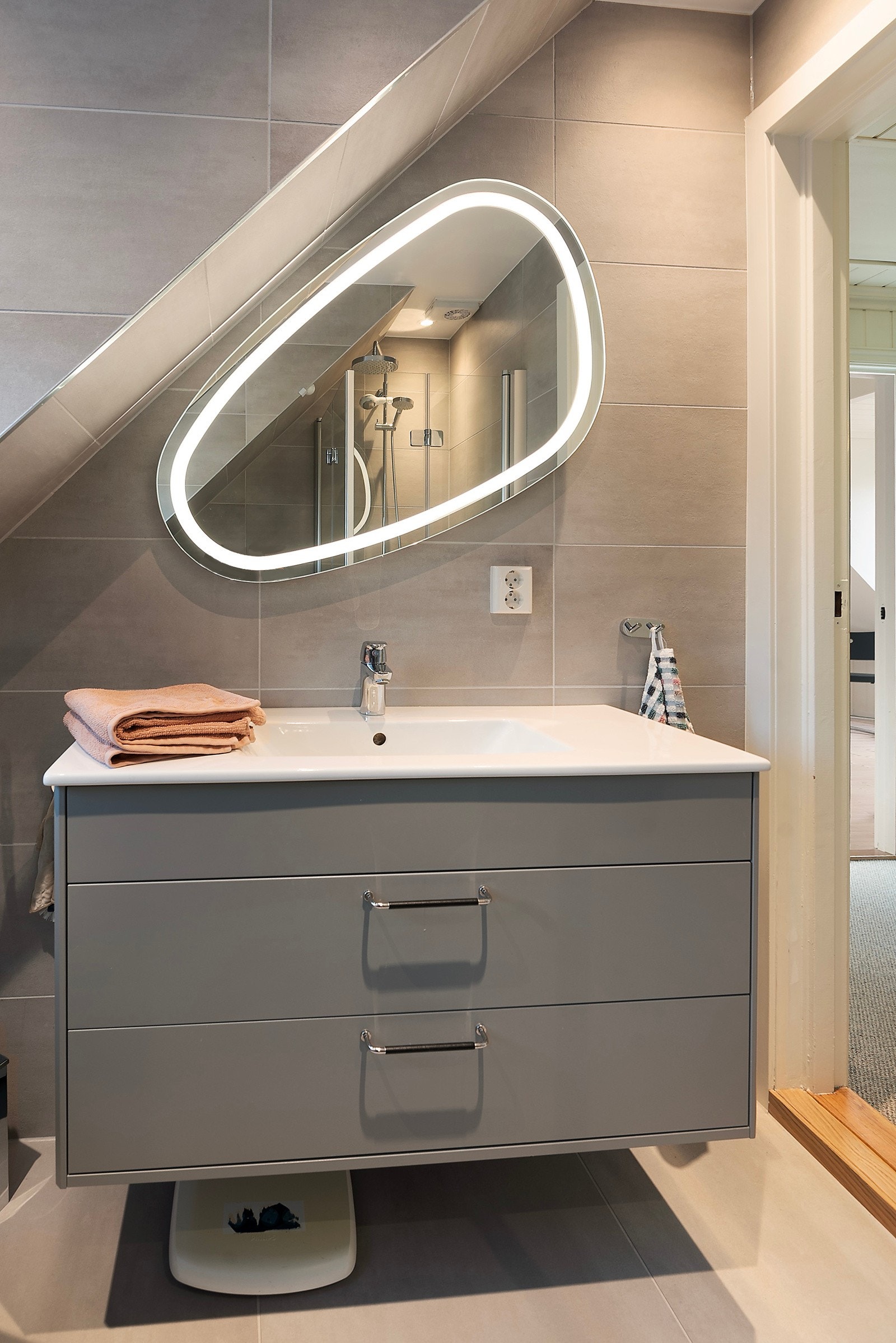 Her har du vegghengt toalett, servantinnredning med skuffer, dusjhjørne og speilet med lys passer perfekt til plasseringen Galleribilde