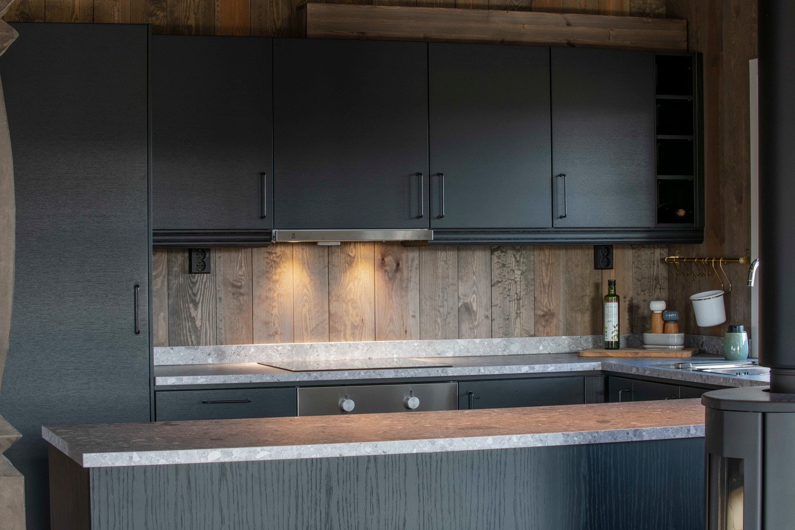 Innredningen har et mørkt og stemningsfullt design med slette fronter, softclose, belysning, laminerte benkeplater og en nedfelt oppvaskkum. Galleribilde