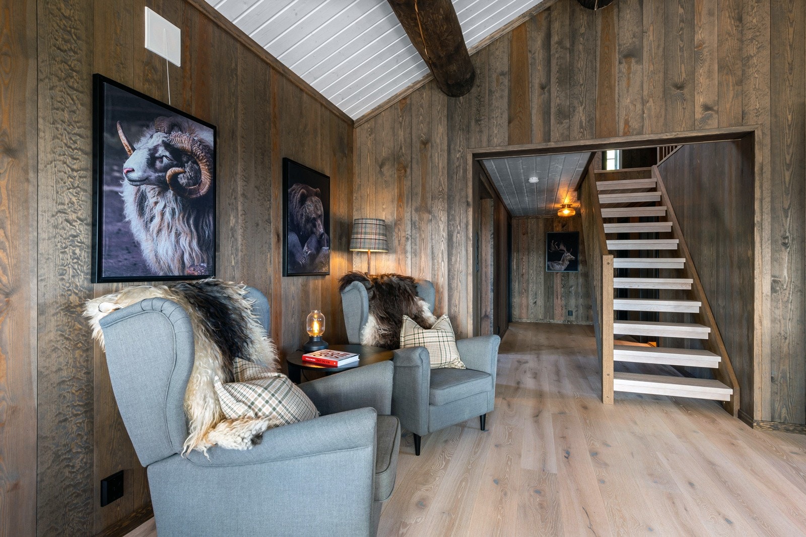 Det er lagt lys, enstavs parkettplank med flytende overgang til kjøkkenet og veggene har trepanel. Galleribilde