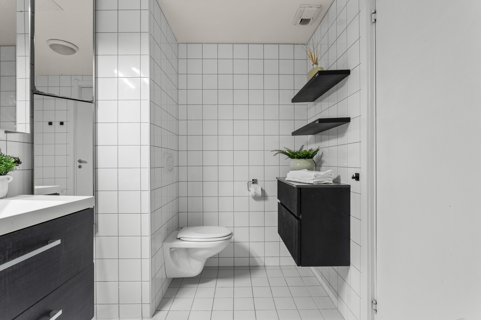 Badet er innredet med dusjhjørne, vegghengt toalett, servant med skuffer og speilskap. Ekstra oppbevaring i vegghengt skap. Galleribilde