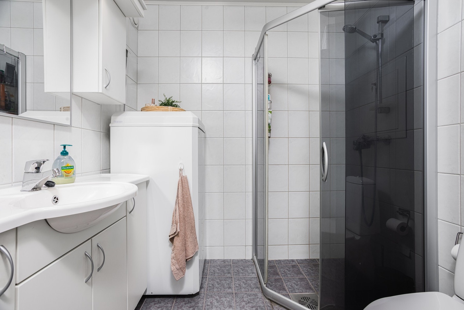 Det flislagte baderommet er utstyrt med toalett, servant, dusjhjørne, VVB og opplegg for vaskemaskin. Galleribilde