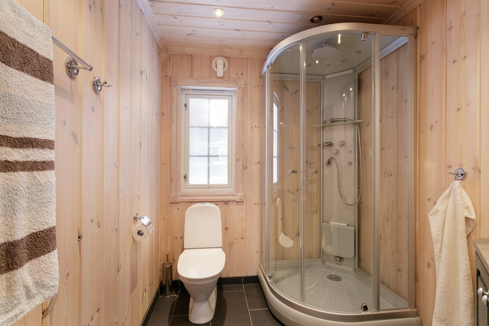 Badet er beliggende mot vest. Hjørneinnredning med nedfelt servant, speilskap over servant, toalett og dusjkabinett med steam (kabinettet er ikke koblet til strøm). Elektrisk styrt vifte. Galleribilde