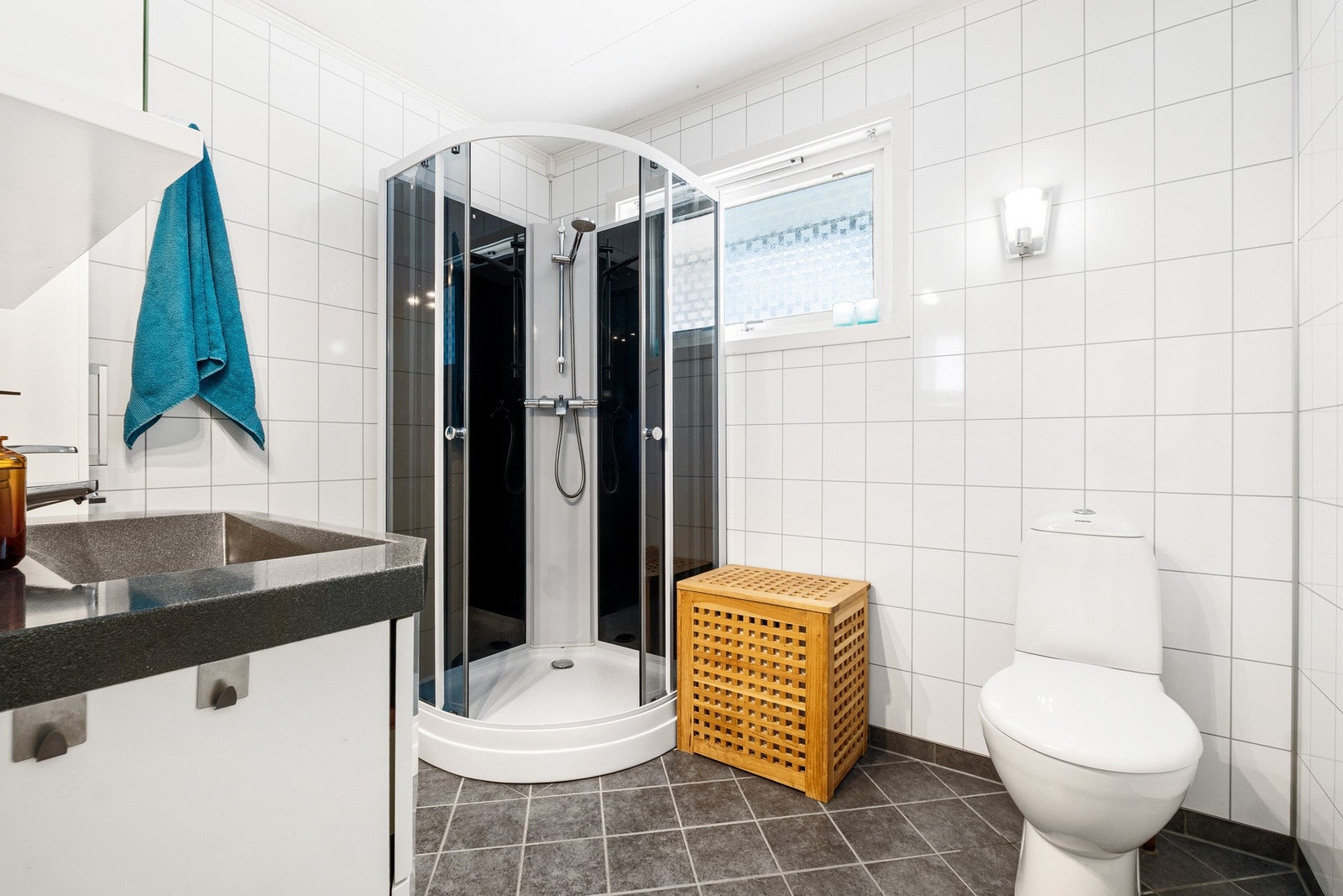 Badet har en tidløs utstråling med hvite vegger og mørke fliser på gulvet. Galleribilde