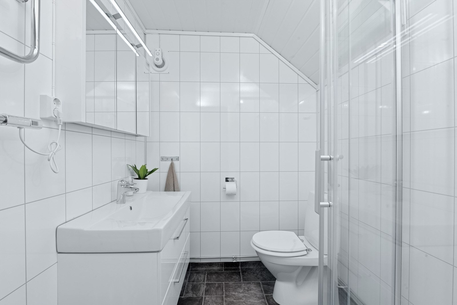 Bad i kjeller med våtromsplater på vegger og himlingsplater. Vinylbelegg på gulvet med termostatstyrte elektriske varmekabler. Galleribilde