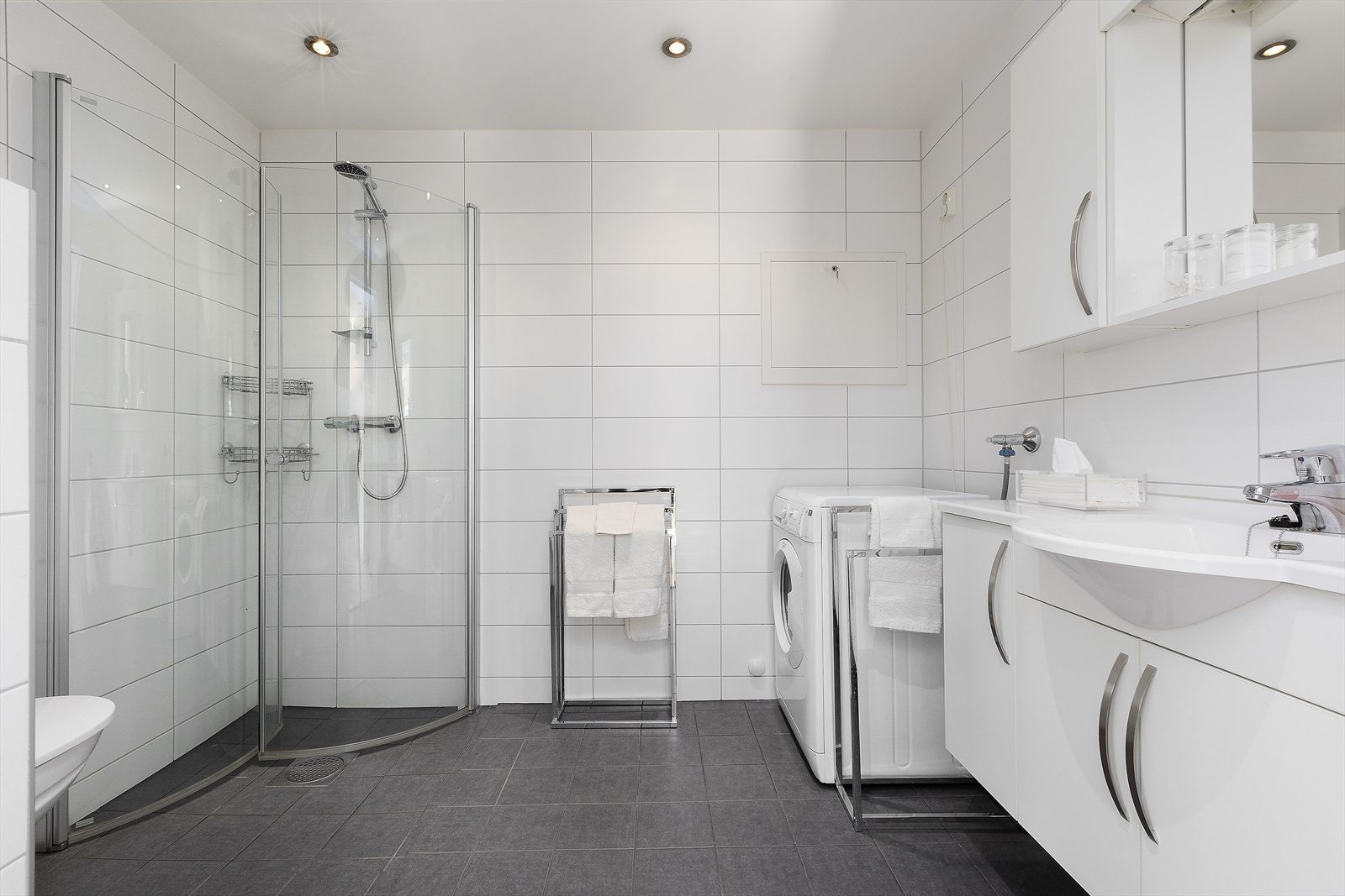 Badet er lekkert og stilrent innredet med lyse fliser og varmekabler i gulv. Galleribilde