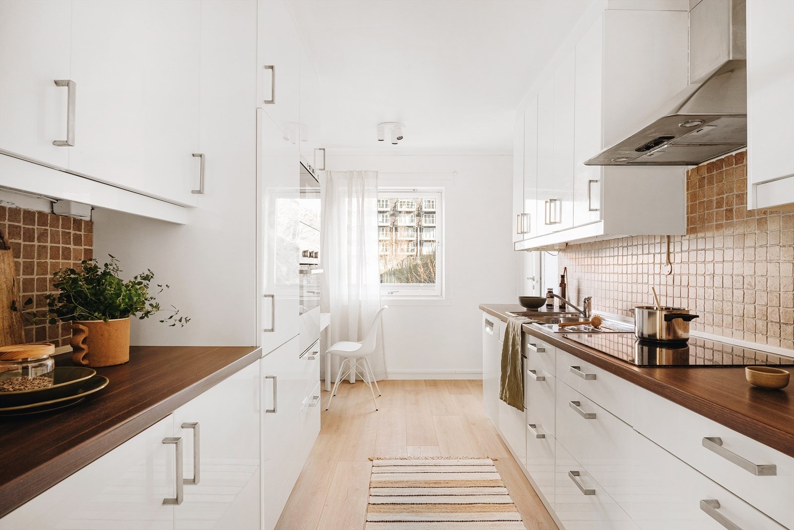 Kjøkken i lys utførelse med IKEA innredning fra 2010. Kjøkkeninnredningen består av slette hvite fronter og laminat benkeplate med stål vaskekum. Galleribilde