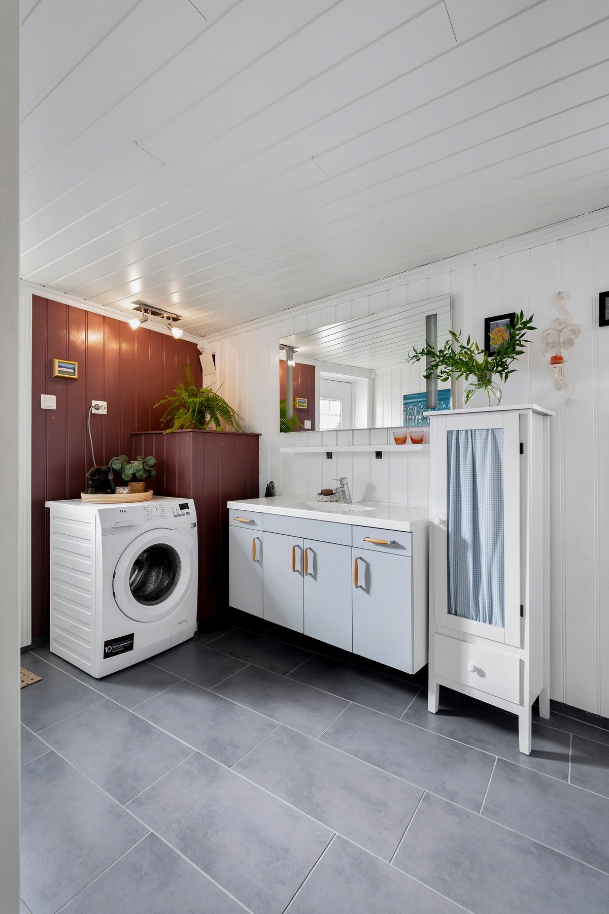 Bad i 2. etasje med grått flisgulv, vaskemaskin og lys servant. Galleribilde