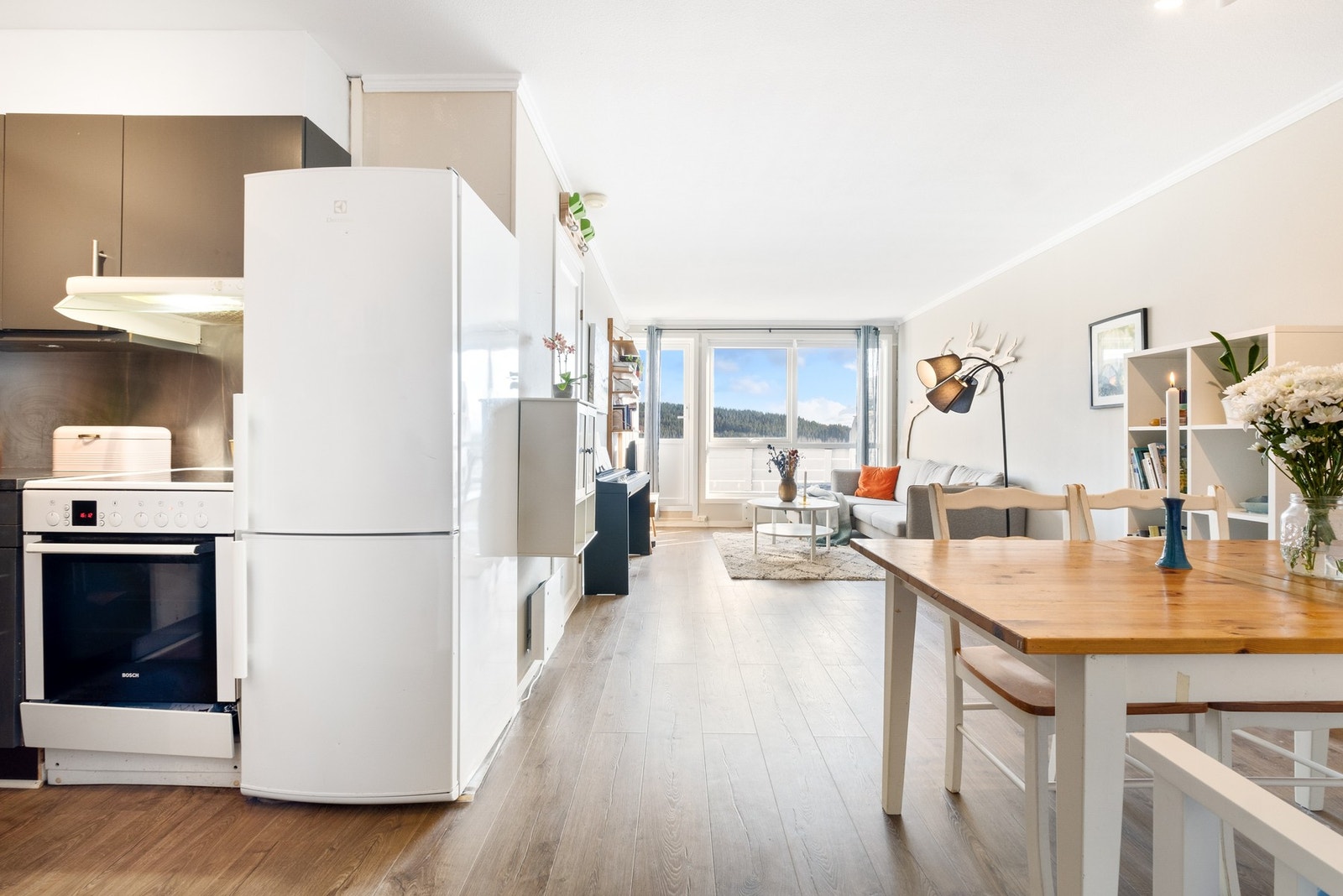 Innbydende stue med store vindusflater i enden som bidrar til et lyst og pent uttrykk Galleribilde